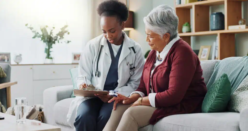 Black doctor consulting with older patient in her home