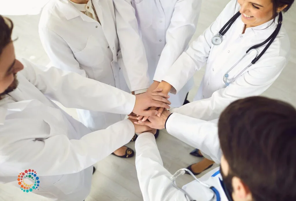 Groups of doctors in labcoats in a circle with hands in
