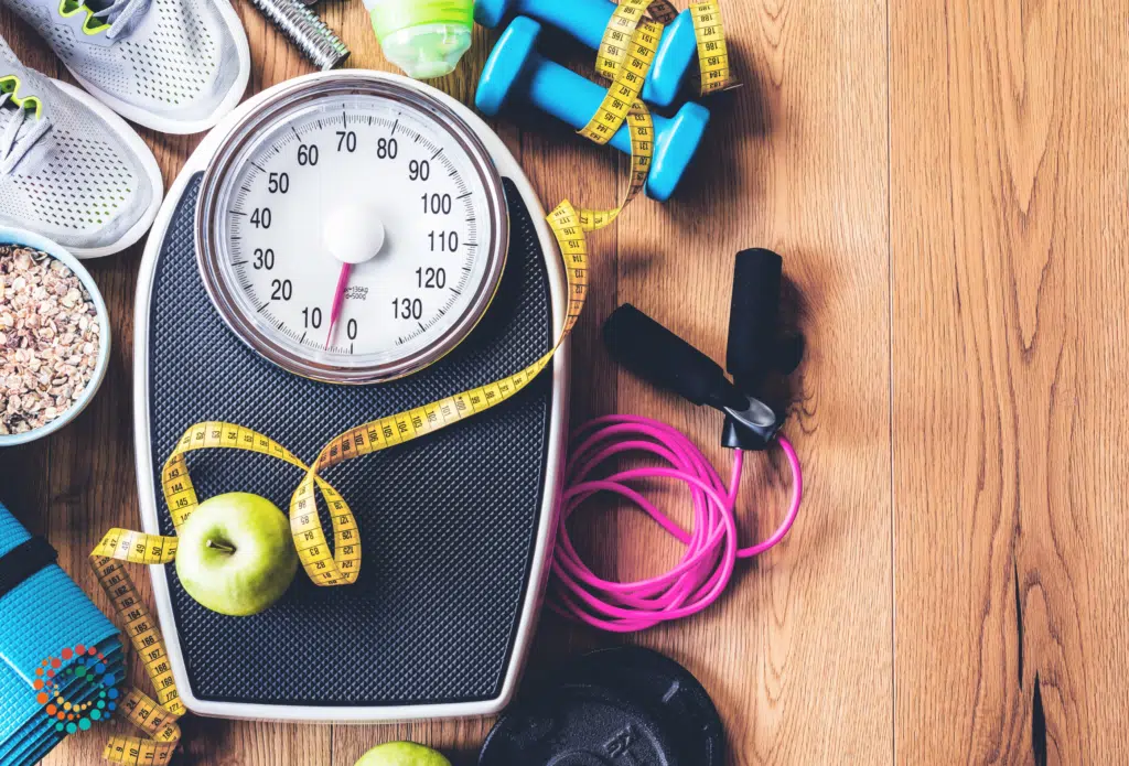 Scale surrounded by sneakers and other fitness gear